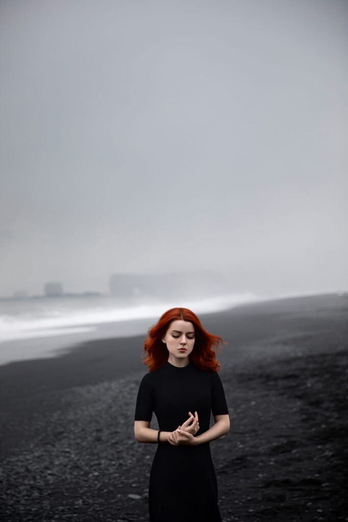 Портрет девушки с рыжими волосами на фоне туманного пляжа