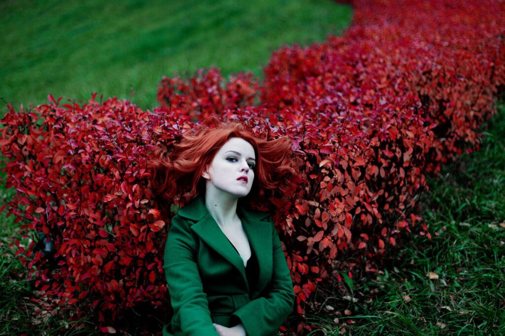 Рыжеволосая девушка на фоне красных кустов