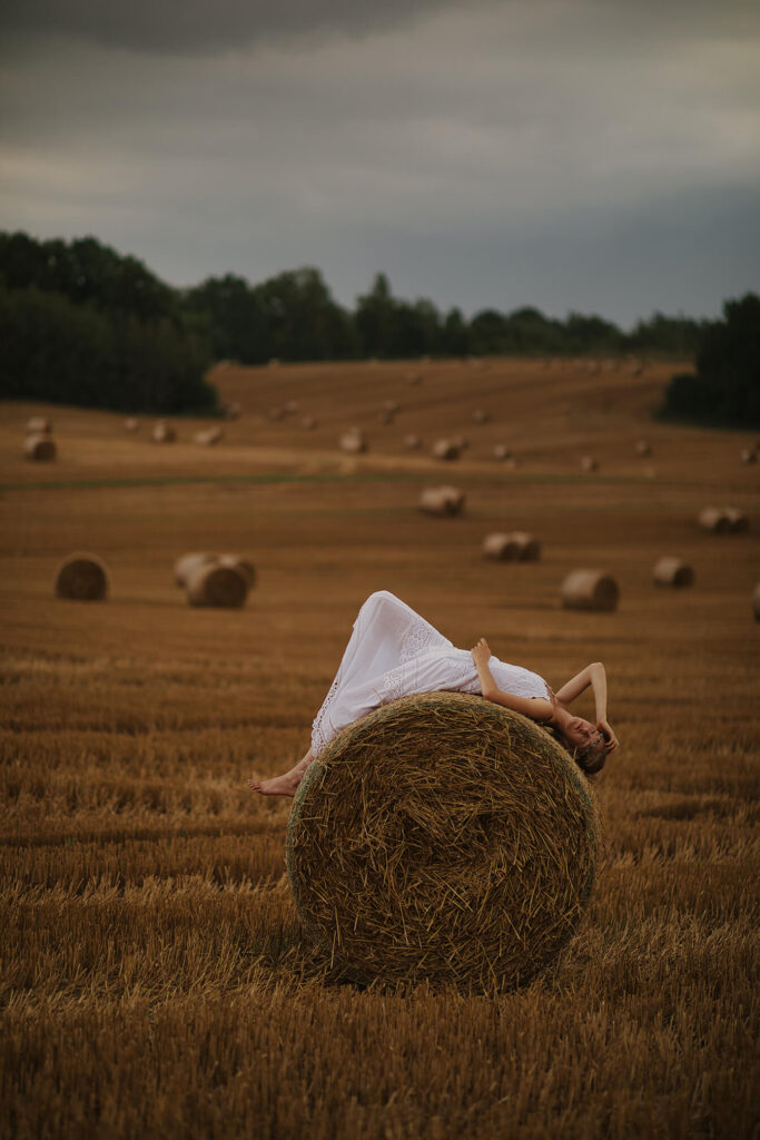 Девушка позирует у стога сена
