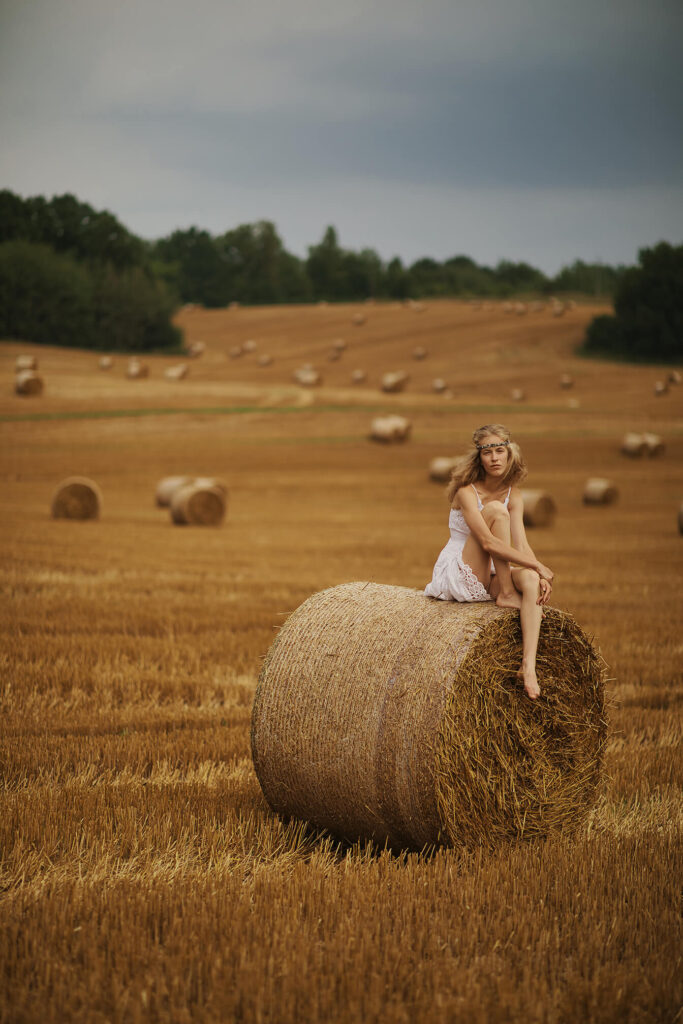 Девушка позирует у стога сена