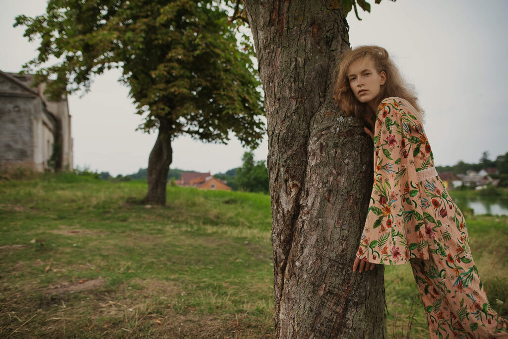 Девушка, сидящая под деревом возле старого дома